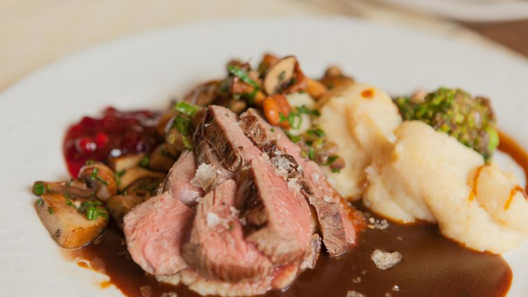 Ein köstlicher Teller mit gebratenem Fleisch, serviert mit Püree und Gemüse. Dazu gibt es eine appetitliche Sauce und Cranberrysoße.