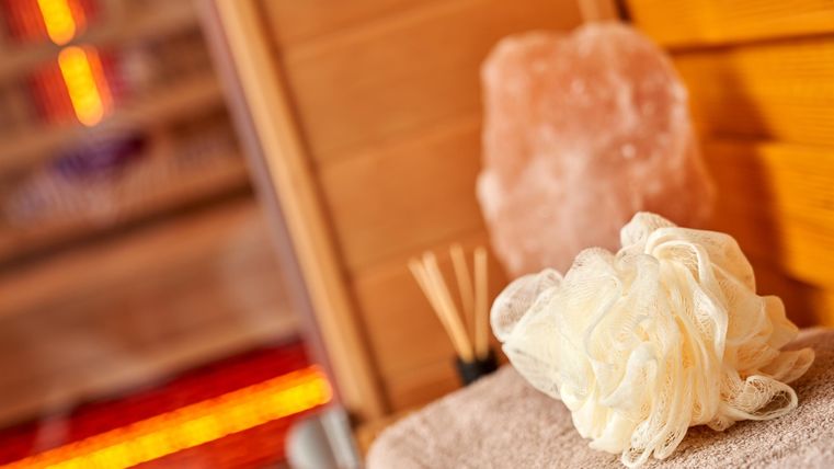 Ein entspannender Spa-Bereich mit einer weißen Duschschwamm und einem Salzkristall. Die warmen Holztöne schaffen eine beruhigende Atmosphäre.