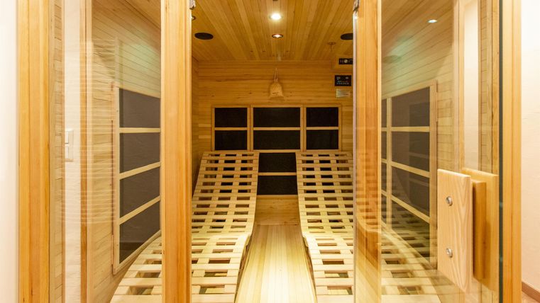 Eine helle Sauna mit Holzverkleidung und Liegen aus Holz. Die angenehme Atmosphäre lädt zur Entspannung ein.