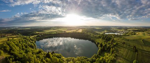 Luftaufnahme von zwei Maaren in einer grünen Landschaft bei Sonnenuntergang.