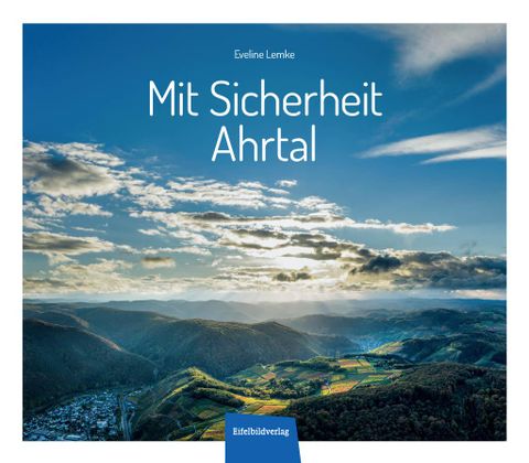Eine beeindruckende Landschaft mit Hügeln und einem klaren blauen Himmel. Unten ist eine kleine Stadt zu sehen, umgeben von grünen Feldern.