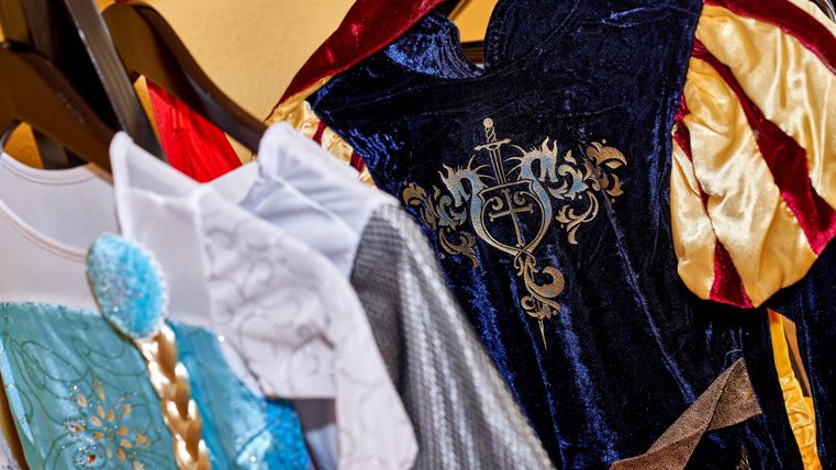 Bunte Kinderkostüme hängen an einem Kleiderständer. Die Outfits sind in verschiedenen Stilen und Farben gestaltet.