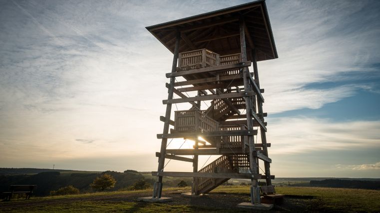 Holzaussichtsturm bei Sonnenuntergang mit weitem Blick über die Landschaft.