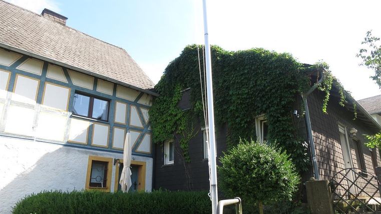 Ein charmantes Gebäude mit einem traditionellen Fachwerkstil und grünem Efeu. Der Garten ist gepflegt und bietet eine einladende Atmosphäre.