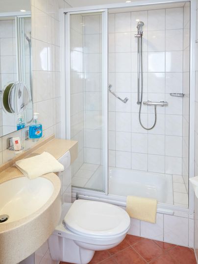 Ein modernes Badezimmer mit Dusche und Waschbecken. Saubere Fliesen und helle Farben schaffen eine einladende Atmosphäre.