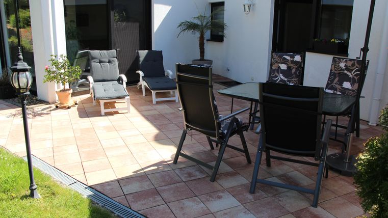 Ein gemütlicher Patio mit modernen Gartenmöbeln und einer schönen Pflanze. Der Bereich ist gut beleuchtet und ideal zum Entspannen im Freien.