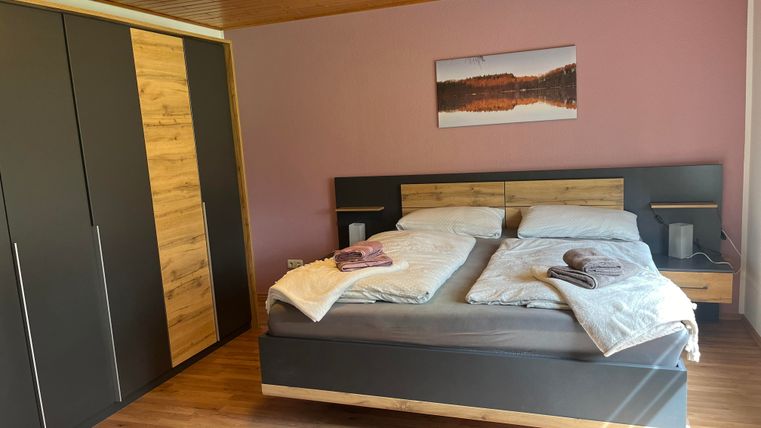 Ein gemütliches Schlafzimmer mit einem großen Doppelbett und modernem Holzschrank. Die Wände sind in sanften Farben gestrichen, und ein Bild hängt über dem Bett.