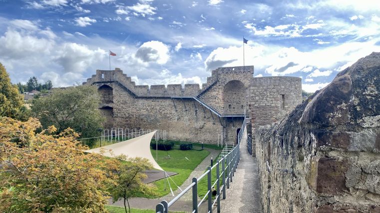<p>Begehbare hohe Stadtmauer aus Stein in Hillesheim, daran grenzt eine Grünfläche an.</p>