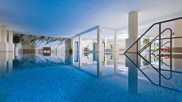 Ein moderner Schwimmbereich mit blauem Wasser. Das helle Umfeld schafft eine entspannende Atmosphäre.