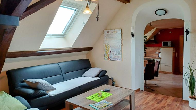 Ein helles Wohnzimmer mit bequemen Sofas und einem großen Fenster. Der Raum hat einen modernen, einladenden Stil mit hellen Holzböden.