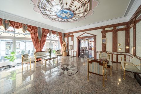 Ein eleganter Lobbybereich mit einem marmornen Boden und reich verzierten Fenstern. Die geschmackvolle Einrichtung und die Kunstwerke verleihen ihm einen luxuriösen Charme.