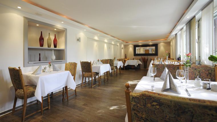 Ein elegantes Restaurant mit Tischdecken und dekorierten Tischen. Der Raum ist hell und modern gestaltet.