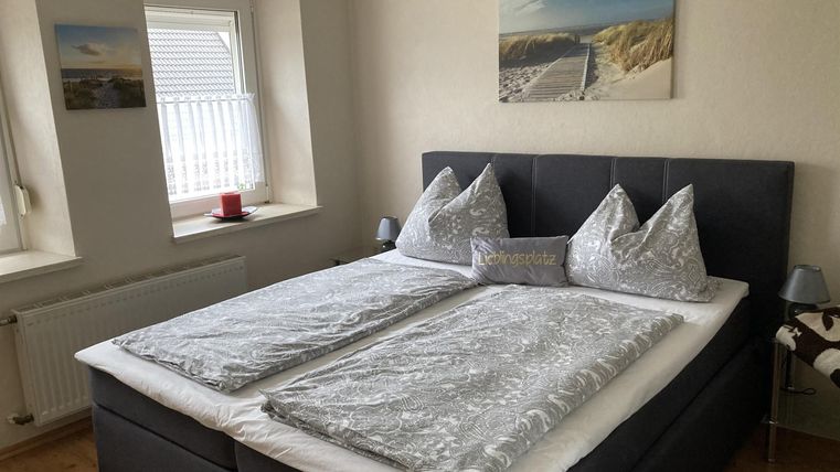 Ein gemütliches Schlafzimmer mit einem großen Doppelbett und eleganten Kissen. An den Wänden hängen Bilder, und das Zimmer hat ein einladendes Ambiente.
