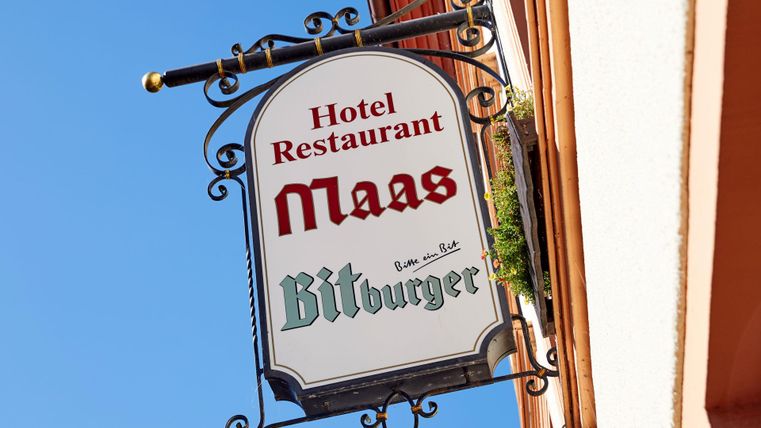 Ein Schild des Hotels und Restaurants Maas. Es zeigt die Bitburger-Brauerei als Partner.