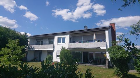 Ein modernes zweistöckiges Gebäude umgeben von Grün. Der Himmel ist klar und blau mit ein paar Wolken.