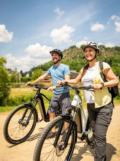 Zwei Personen mit Fahrrädern im Kurpark Gerolstein bei sonnigem Wetter.