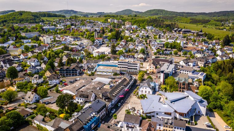 Eine luftige Ansicht einer kleinen Stadt mit vielen Häusern und grünen Hügeln im Hintergrund. Die Umgebung ist lebendig und gut besiedelt.