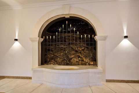 Ein eleganter Brunnen mit einer Steinwand und einem filigranen Gitter. Sanfte Beleuchtung schafft eine ruhige Atmosphäre.