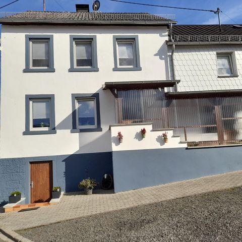 Ein modernes Haus mit blauen und weißen Wänden. Es hat große Fenster und einen kleinen Vorgarten.