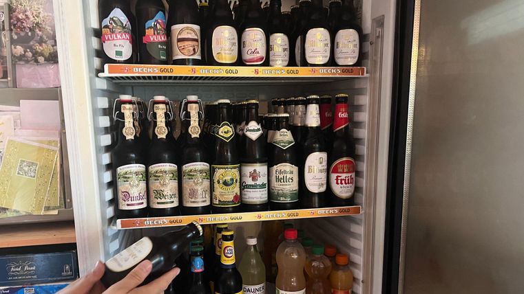 Ein Kühlschrank voller verschiedener Bierflaschen und alkoholischer Getränke. Diverse Marken und Sorten sind ordentlich aufgereiht.