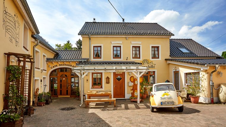 A yellow café called 'Mausefalle', a small car parked in front of it.