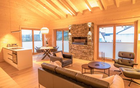Ein modernes Wohnzimmer mit Holzwänden und großen Fenstern. Es gibt eine gemütliche Sitzecke, einen Esstisch und einen eleganten Kamin.