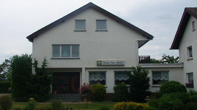 Ein modernes Wohnhaus mit hellem Anstrich und zwei Etagen. Der Garten ist gut gepflegt und mit verschiedenen Pflanzen angelegt.