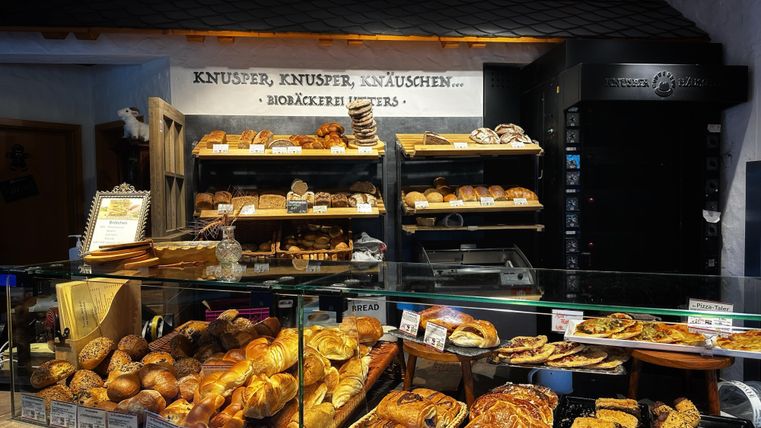 Eine Bäckerei mit einer Vielzahl von frischen Backwaren. Brote, Gebäck und süße Leckereien sind ansprechend präsentiert.