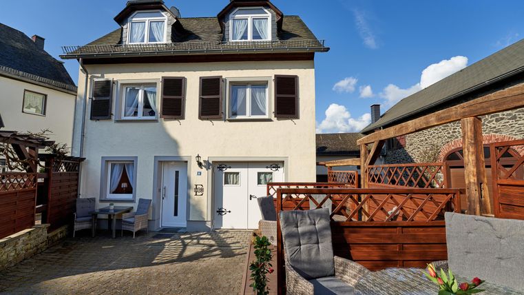 Ein charmantes Haus mit einem klaren Himmel im Hintergrund. Der Außenbereich ist gut gestaltet und lädt zum Entspannen ein.
