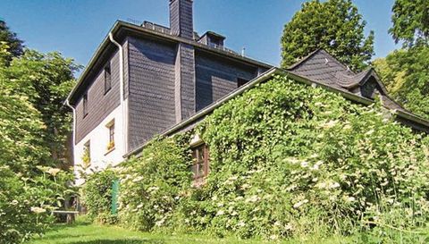 Ein charmantes Haus, umgeben von üppigem Grün und Büschen. Die Fassade ist teilweise mit Pflanzen bewachsen, was eine naturnahe Atmosphäre schafft.