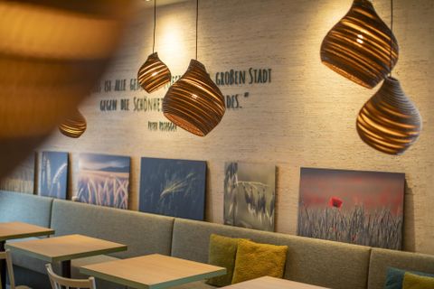 Ein modernes Restaurant mit gemütlicher Atmosphäre. Deckenlampen und dekorative Wandbilder schaffen ein einladendes Ambiente.