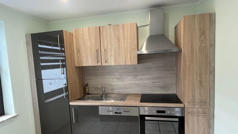Moderne Küche mit Holz- und Glaselementen. Sie verfügt über einen Herd, einen Kühlschrank und eine Spüle.