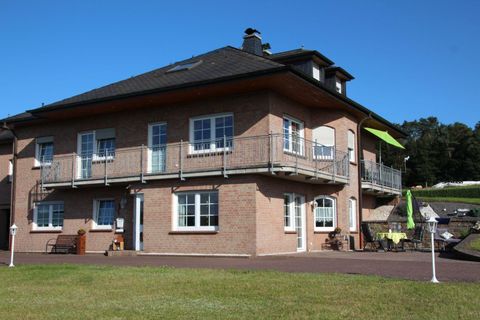 Ein modernes Haus mit einem großen Balkon und mehreren Fenstern. Der Garten ist gut gepflegt und lädt zum Entspannen ein.