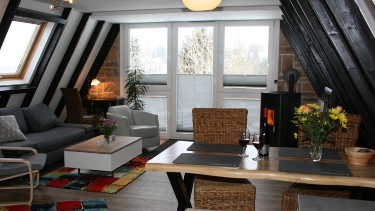Eine gemütliche Wohnung mit modernen Möbeln und einem großen Tisch. Große Fenster sorgen für viel Tageslicht und eine einladende Atmosphäre.