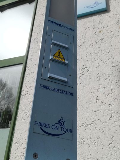 Ein elektronisches Infoterminal an einer Wand. Es zeigt eine Warnungssymbol und Informationen zu einem Fahrradverleih.