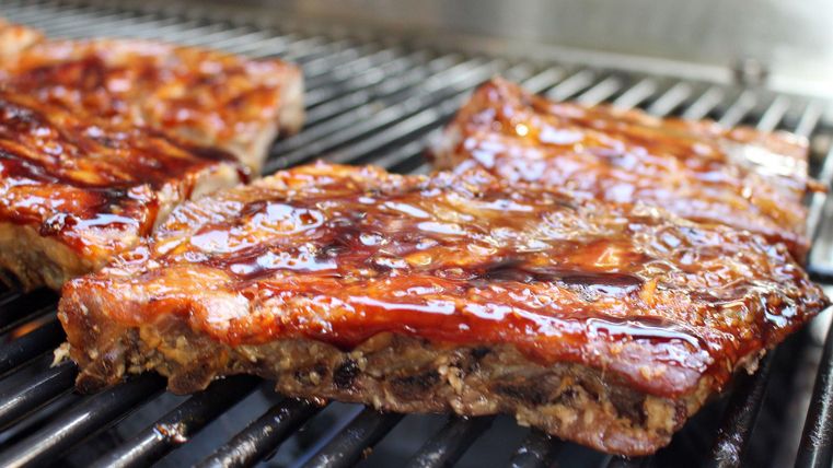 Gegrilltes Fleisch mit einer glänzenden Marinade auf einem Grillrost. Leckere BBQ-Rippchen in appetitlicher Farbe.
