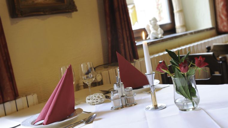 Ein eleganter Tisch in einem Restaurant mit roten Servietten und frischen Blumen. Das Ambiente ist einladend und gemütlich.