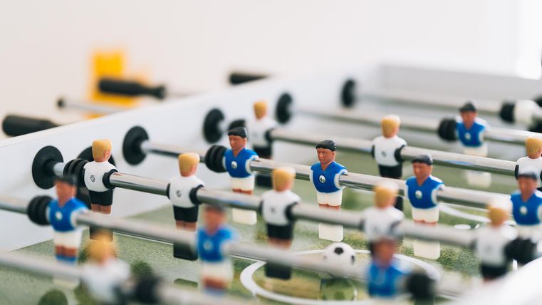 Ein Tischfußballspiel mit vielen bunten Figuren. Die Spieler stehen auf einem grünen Spielfeld und sind bereit zum Spielen.
