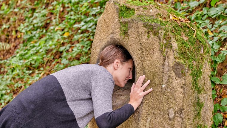 Person steckt Kopf in einen Summstein am Achtsamkeitspfad Kleine Kyll.