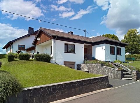 Ein modernes Einfamilienhaus mit hellem Anstrich und einem gepflegten Garten. Die Umgebung ist grün und einladend.