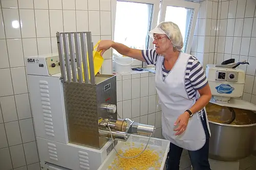 Frau in Hygienekleidung produziert Nudeln am Automat